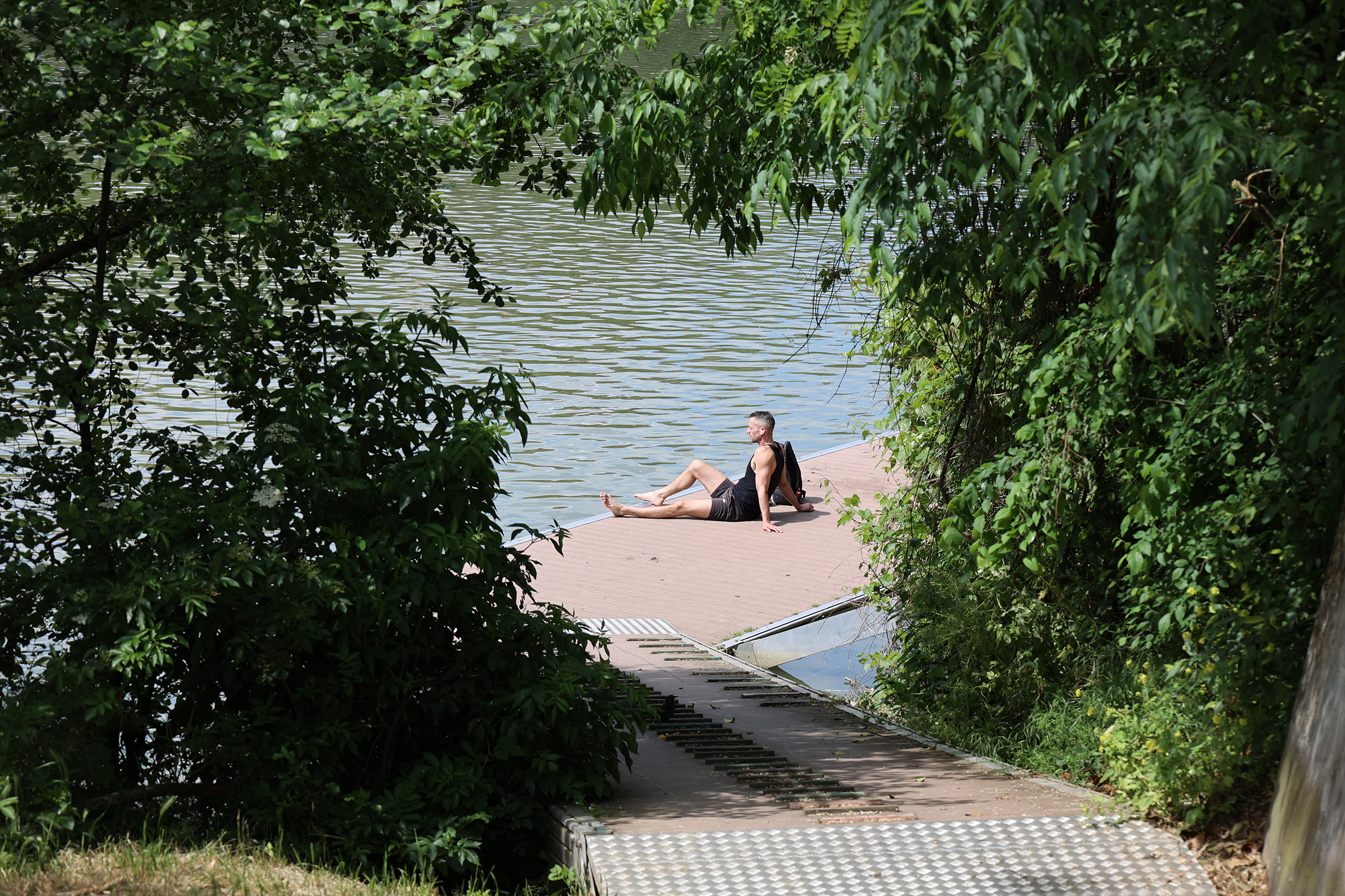Ein Mann, der am begrünten Ufer der Garonne auf der Île du Ramier in Toulouse sitzt.