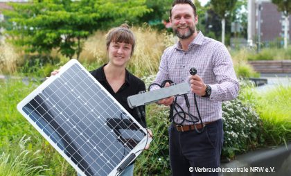 Foto von einer Frau und einem Mann mit einer Solarpanele für Sonnenenergiegewinnung