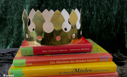 Foto von einem Stapel Kinderbücher mit einer Papierkrone darauf.