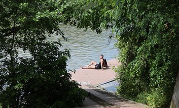 Ein Mann, der am begrünten Ufer der Garonne auf der Île du Ramier in Toulouse sitzt.
