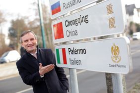 Oberbürgermeister Geisel deutet auf das neue Straßenschild mit den Partnerstädten