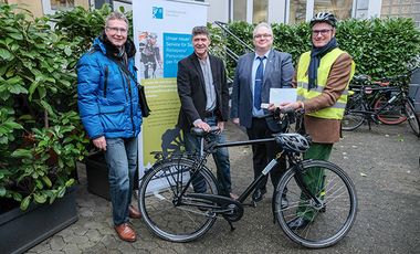 (v. l.) Amtsleiter Harald Wehle, Holger Lorenz von Rotrunner GmbH, Michael Müller und Beigeordneter Prof. Andreas Meyer-Falcke bei der Zustellung des neuen Personalausweises per Fahrrad