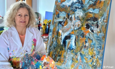 Cida Moraes vor einer bunten Leinwand