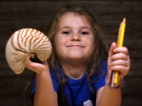 Mädchen hält Stifte und Nautilusschale in den Händen