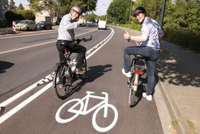 Foto von Testen das neue Teilstück des geschützten Radweges auf der Karlsruher Straße: Mobilitätsdezernent Jochen Kral (li.) und Florian Reeh, Leiter des Amtes für Verkehrsmanagement, die auf dem Fahrrad über den neuen Radwegfahren.