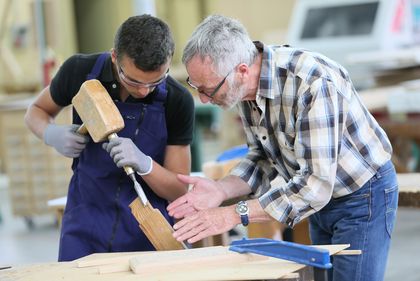 Lehrling und Ausbilder arbeiten an einem Stück Holz, © goodluz, fotolia