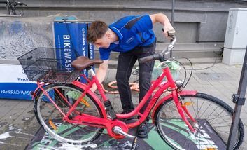 Foto von einem Mann der ein rites Fahrrad reinigt.