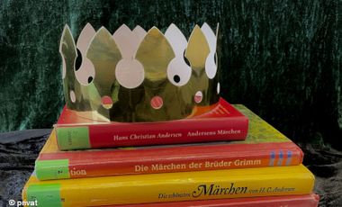 Foto von einem Stapel Kinderbücher mit einer Papierkrone darauf.