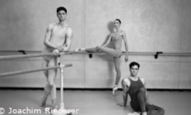 Schwarzweiß Foto mit zwei Balletttänzern und einer Ballettänzerin in einem Probenraum mit Stange und Spiegel