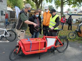 3 persionen unterhalten sich an einem Lastenrad