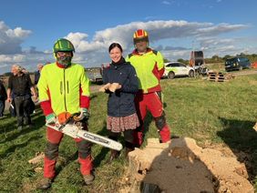 Franziska Roger Bravo (M.) vom Garten-, Friedhofs- und Forstamt mit Mitarbeitern des Amtes beim Verteilen kleiner Stücke aus dem Holz des Baumstumpfs, Foto: LHD.