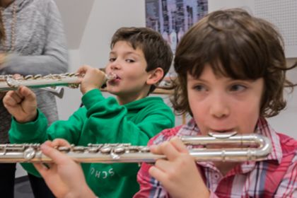 Foto von Kindern, die im Instrumentenkarussell die Querflöte ausprobieren.