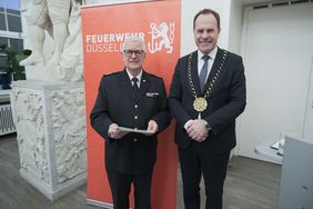 Oberbürgermeister Dr. Stephan Keller überreicht Thomas Jeziorek, ehemaliger Leiter der Werksfeuerwehr des Flughafens, die Feuerwehrehrennadel. Foto: Michael Gstettenbauer