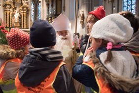 Die Kinder übergaben dem Nikolaus ihre selbstgebastelten Geschenke, die den Menschen im Caritas-Hospiz in Garath zukommen werden. Foto: Uwe Schaffmeister