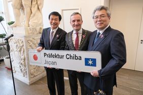 Kensaku Morita, Gouverneur der Präfektur Chiba, Oberbürgermeister Thomas Geisel und Mitsuru Yoshimoto von Chibas Präfekturparlament mit der neuen Tafel, die an Düsseldorfer Einfahrtstraßen auf die Partnerschaft hinweisen wird. Foto: Michael Gstettenb