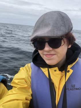 Ein Selfie Kim Zettls: Kim trägt eine gelbe Regenjacke, eine graue Mütze und Sonnebrille. Im Hintergrund ist der Atlantik zu sehen.