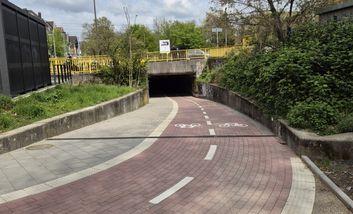 Foto von einem roten Zweirichtungsradweg der durch eine Unterführung führt.