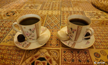 Zwei Kaffeetassen mit Gebäck auf gemustertem Untergrund