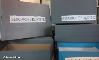 Foto mit Kartons, auf denen "Geschichtenkisten" steht