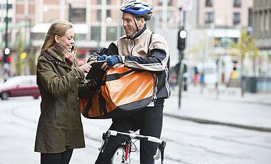 Fahrradkurier bei der Übergabe seiner Sendung 