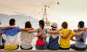 Jugendliche sitzen sich umarmend nebeneinander und schauen auf das Meer