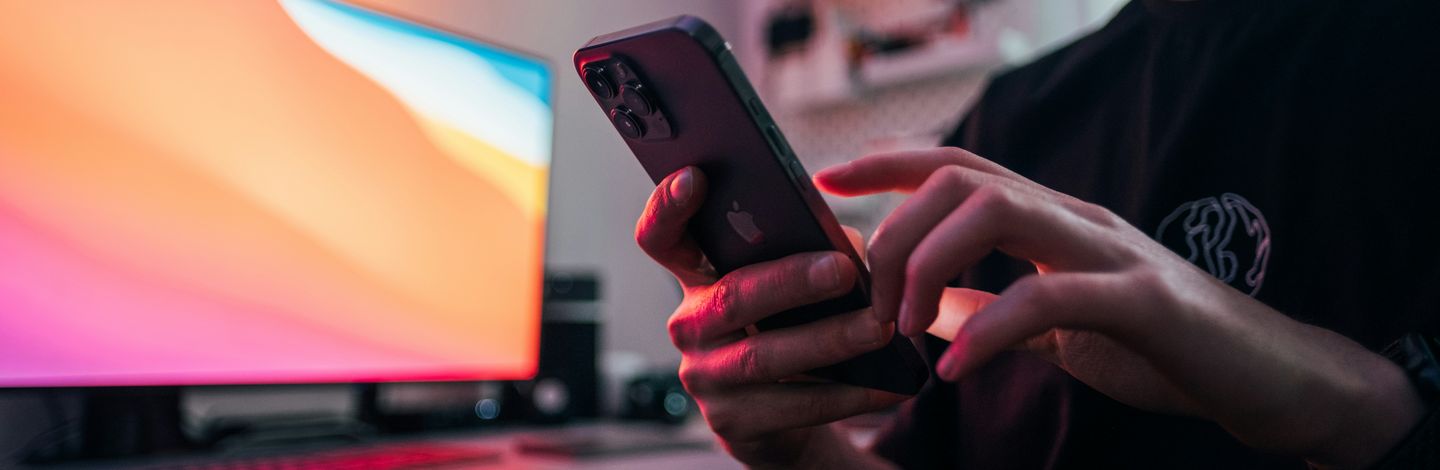 Mann tippt auf einem Smartphone neben einem orange leuchtenden Bildschirm
