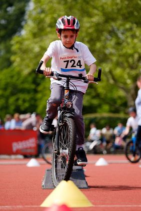 Foto von Jungem der mit seinem Fahrrad durch einen Hindernisparcour fährt.