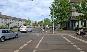 Foto von vielbefahrenem Kreuzungsbereich mit Auto, Rad und Fußverkehr.