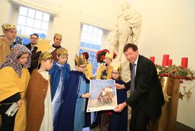 Stadtdirektor Burkhard Hintzsche zeigt mit den Sternsingern das Poster zur diesjährigen Sternsinger-Aktion "Wir gehören zusammen – in Peru und weltweit". Foto: Lammert