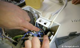 Zwei Hände reparieren ein Gerät