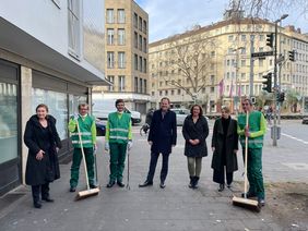 Start des Hilfsprojekts am Stresemannplatz: OB Keller (4.v.r.), Miriam Koch (l.), Evelyn Floryszcak (2.v.r.) und Stephanie Kasten (3.v.r.) mit "den Fegern" Gregorz Kiraga (2.v.l.), Alvin Kajtazovic (3.v.l.) und Frank van Houter (r.) © Landeshauptstadt Düsseldorf/Martin Vornhof