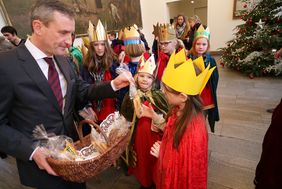 Das Stadtoberhaupt überreicht den Kindern als Dank für ihren Einsatz ein kronenförmiges Gebäckstück.